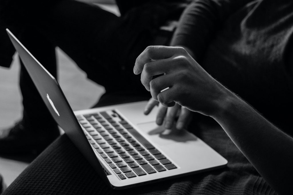 Monochrome photograph of hands and a laptop
